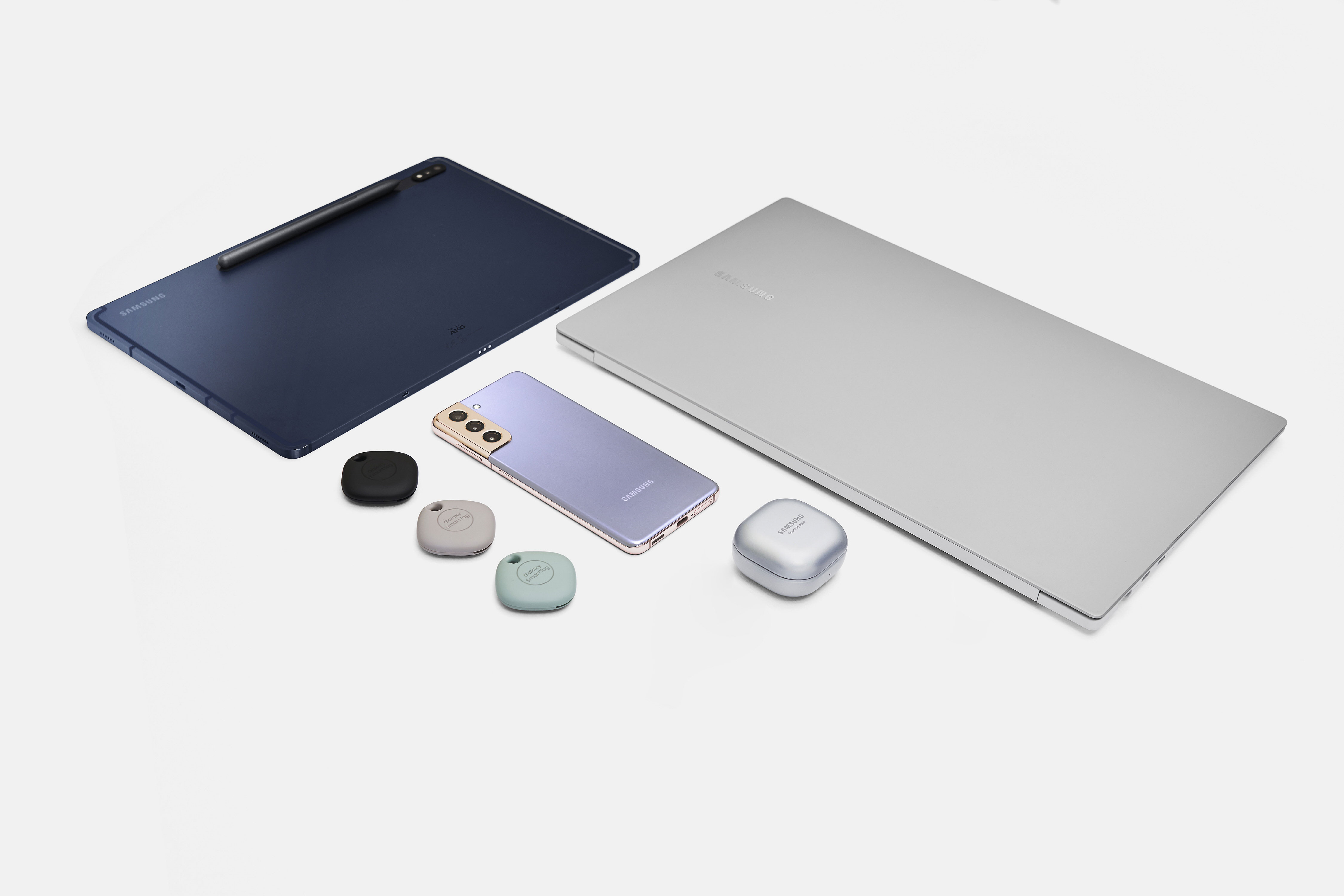 Galaxy Book Pro 15 inch in mystic silver with Galaxy S21 in violet Galaxy Tab S7 Plus in navy Galaxy SmartTags in black oatmeal and mint and Galaxy Buds Pro in silver all together on white surface