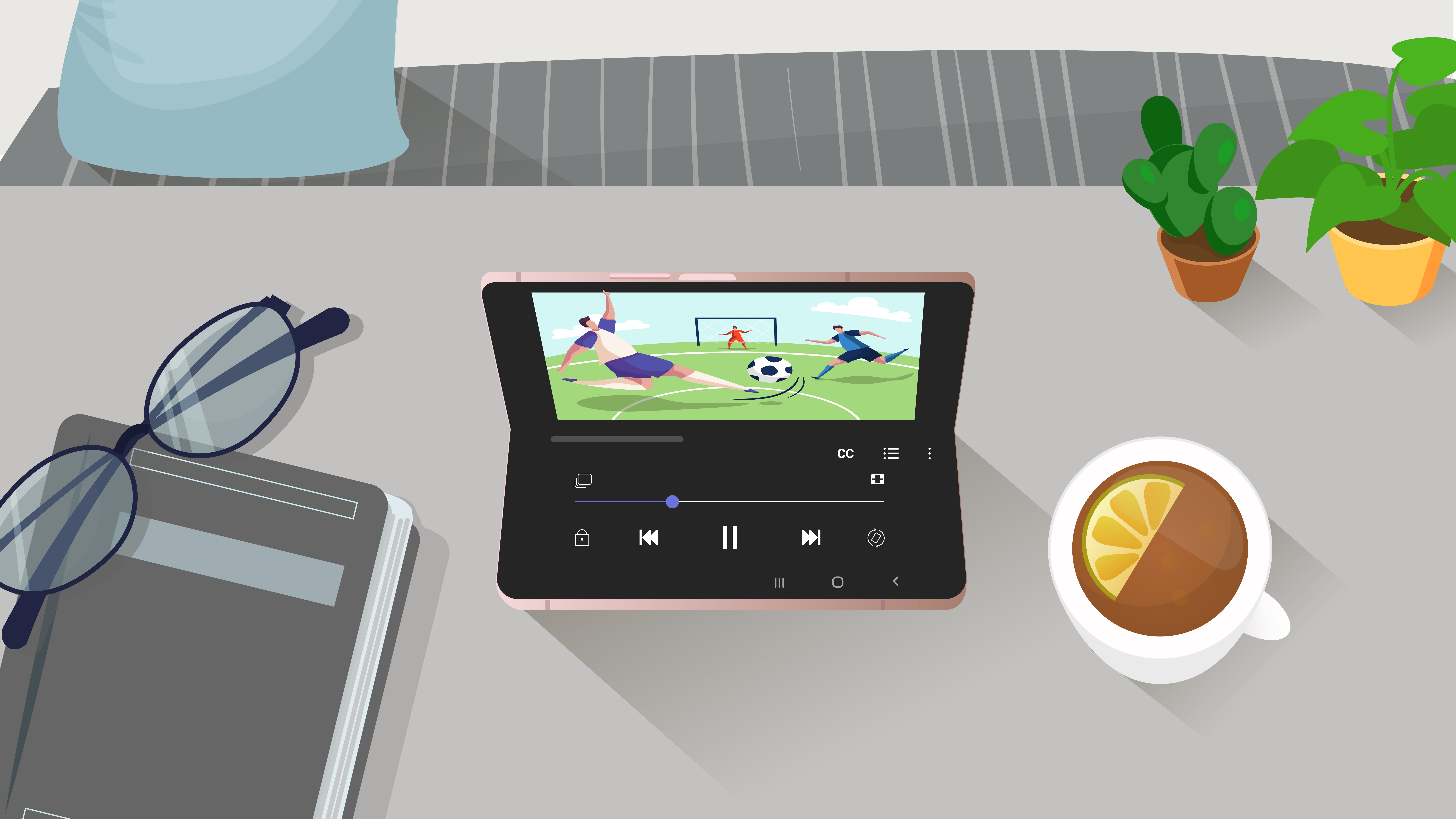 An illustration with a Galaxy Z Fold2 open in a flex mode showing a soccer game on the screen the phone is propped open on a gray table with a cup, notebook, glasses and plants