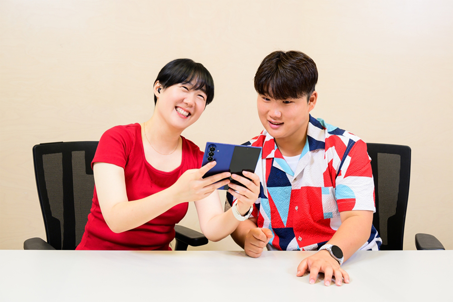Samsung Supporters sit at a table. One of them holds a Galaxy Z Fold7.